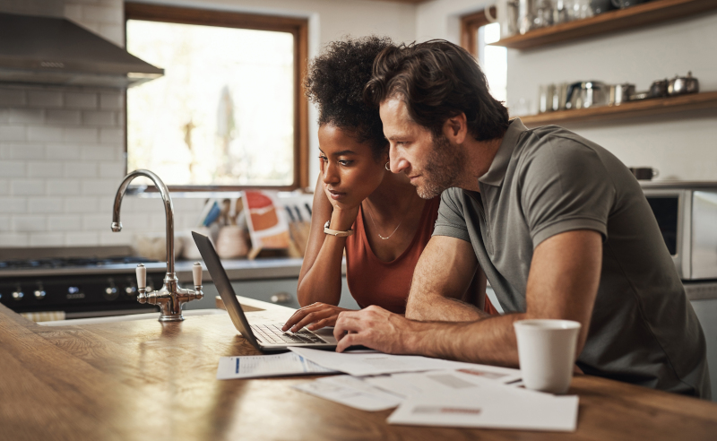 A couple looking for debt consolidation options on a laptop on their kitchen.